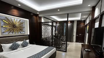 Quarto moderno com uma cama grande, televisão e um detalhe decorativo na parede.