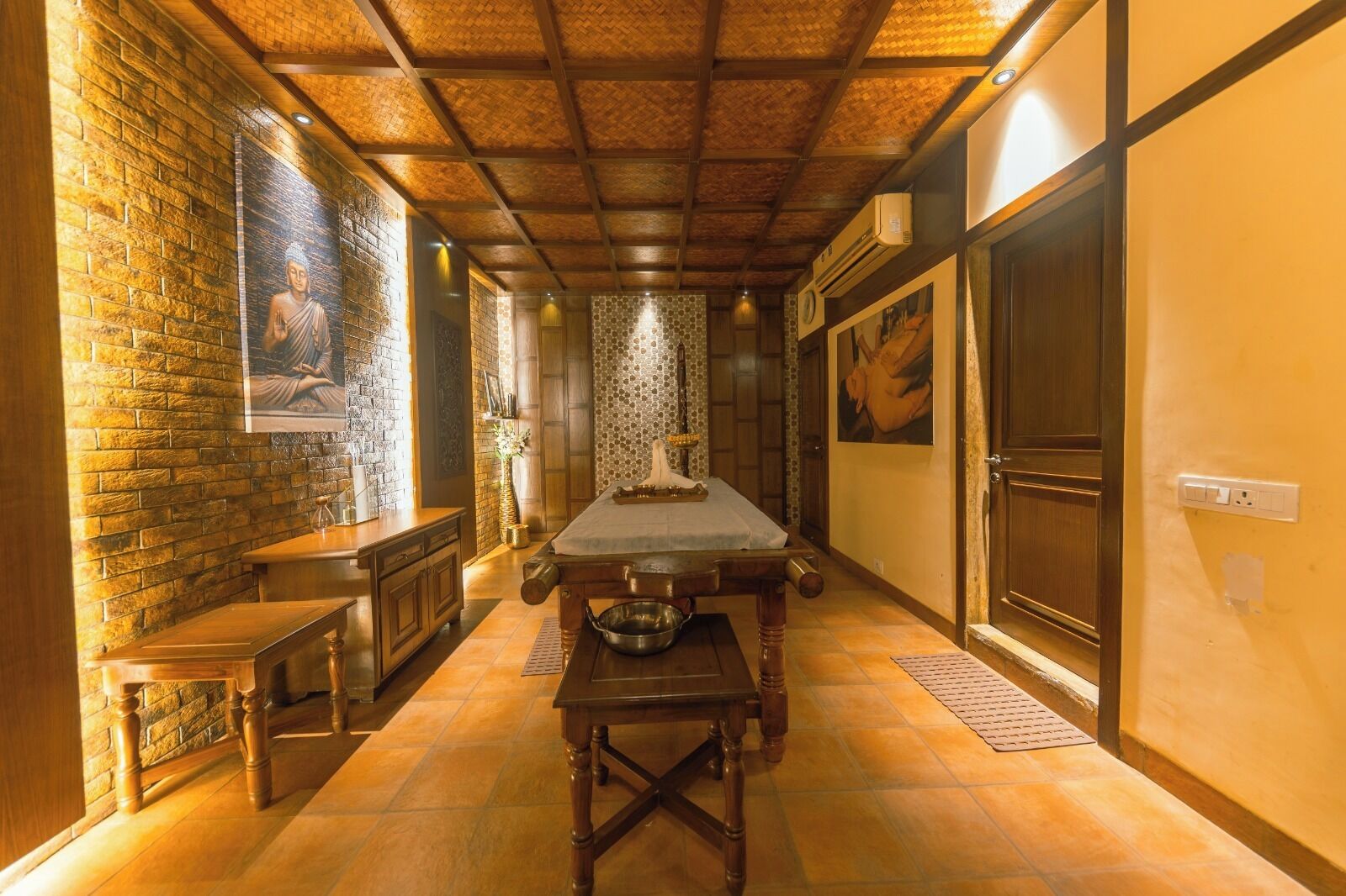 Um corredor estreito, com um banco de madeira à esquerda, uma mesa comprida no centro e uma porta à direita.