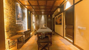 Um corredor estreito, com um banco de madeira à esquerda, uma mesa comprida no centro e uma porta à direita.