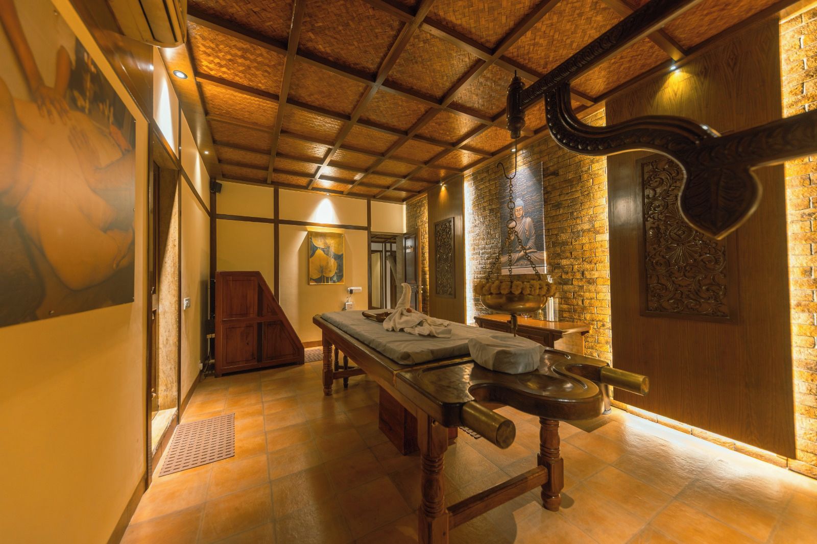 Quarto tradicional com teto de madeira, uma cama grande com cabeceira, um banco de madeira e uma prateleira fixada na parede.