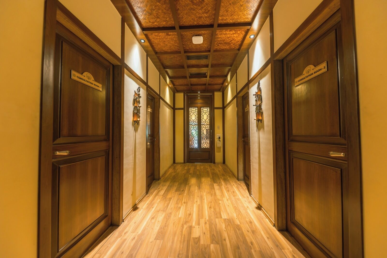 A hallway with wooden doors, a wooden floor, and a ceiling with exposed beams.
