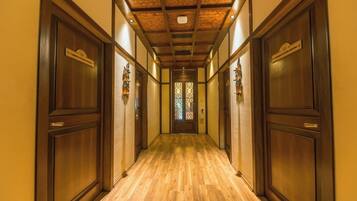 A hallway with wooden doors, a wooden floor, and a ceiling with exposed beams.
