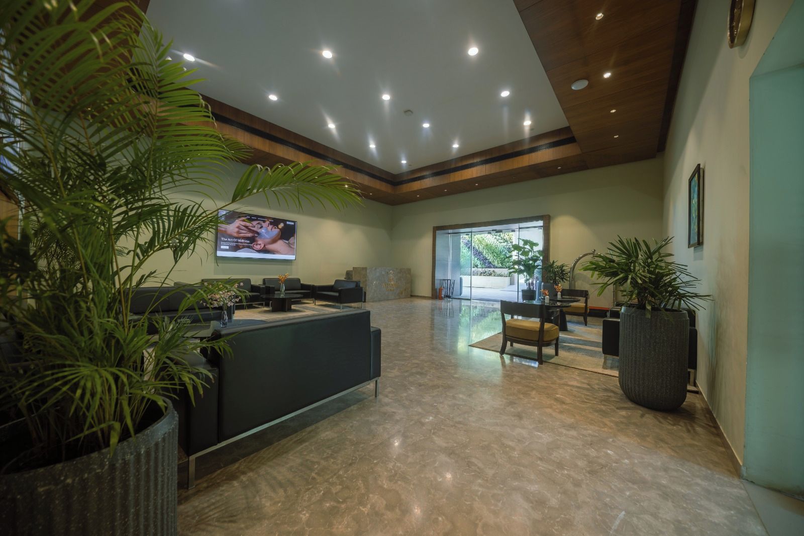 A reception area with a reception desk, seating, potted plants, and a large screen displaying content.