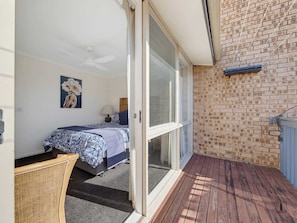 Ein Schlafzimmer mit einem Bett, Deckenventilator, Fenster und einer Ziegelwand.