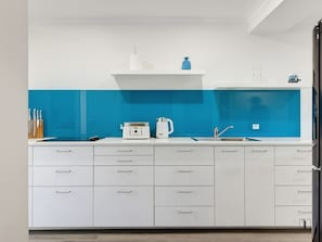 Eine moderne Küche mit weißen Schränken, einer blauen Spritzschutzeinrichtung und Edelstahlgeräten.
