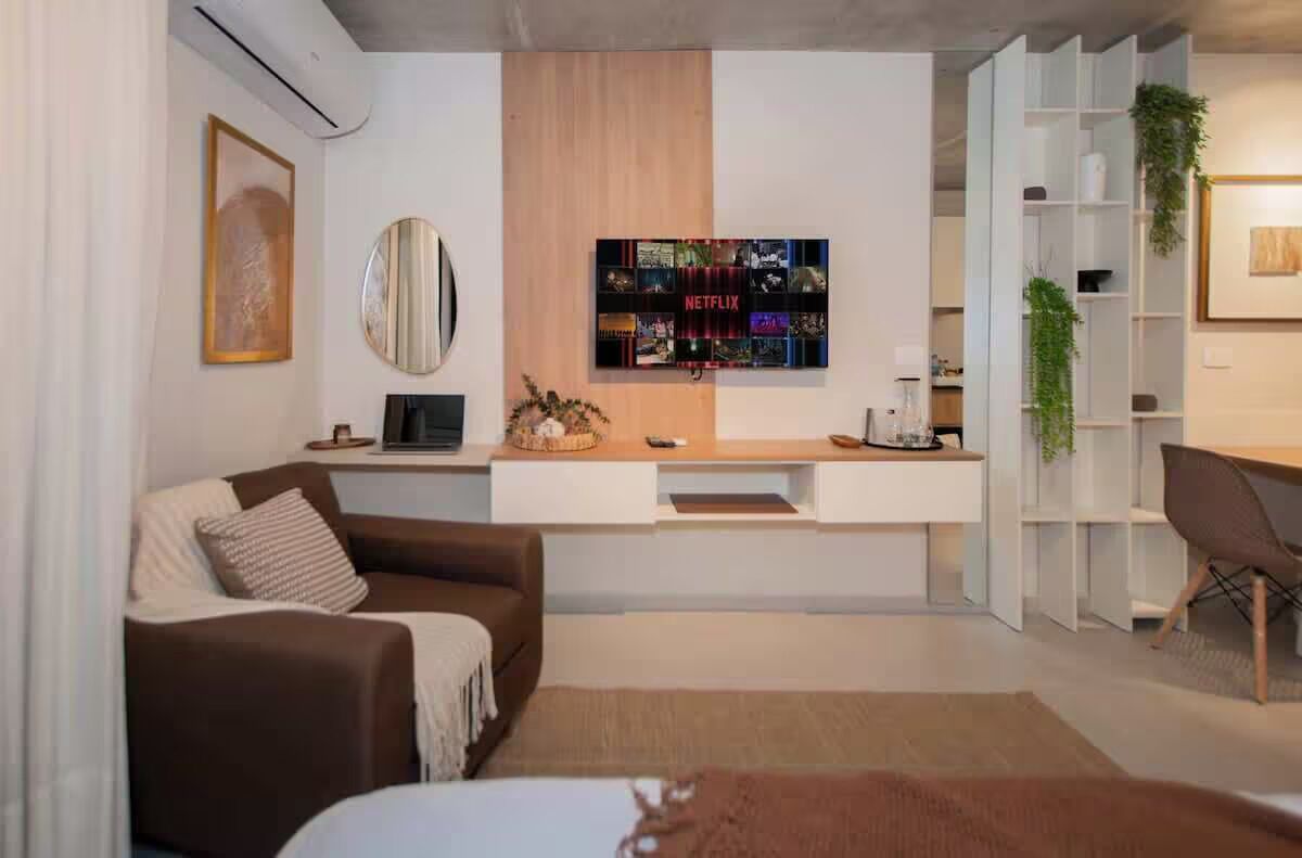Una sala de estar moderna con un sofá, una mesa de centro, un televisor montado en la pared y una estantería.