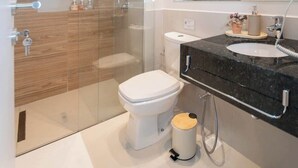 A modern bathroom with a glass shower enclosure, a white toilet, a black countertop with a sink, and a mirror. - Corporate Stays First del Sol - 104 (Asunción)