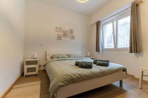 A bedroom with a bed, bedside tables, a window with curtains, and wall-mounted pictures. - Vacation rental in the center of the historic town of Silves with a large rooftop terrace. (Silves)