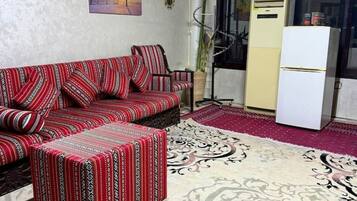 A living room with a sofa, ottoman, and patterned rug.