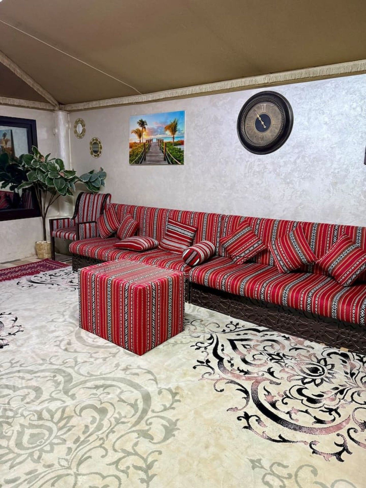 A living room with a sofa, ottoman, and a large rug.