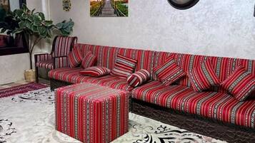 A living room with a sofa, ottoman, and a large rug.
