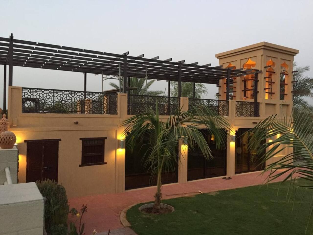 A two-story building with a balcony, palm trees, and a well-lit entrance.