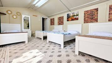 A bedroom with three beds, a patterned carpet, and a brick wall decoration.