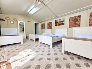 Une chambre avec trois lits, une moquette à motifs et un mur décoré de briques apparentes.