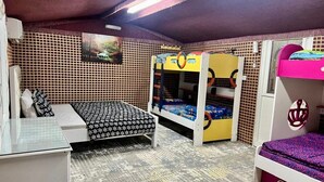 Quarto com beliches, uma escrivaninha e um tapete estampado.