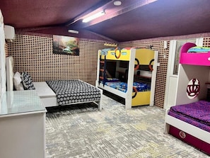 Ein Zimmer mit Etagenbetten, einem Schreibtisch und einem gemusterten Teppich.