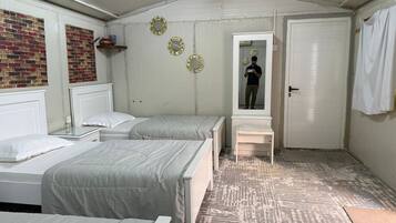 A room with two beds, a bench, a door, and a mirror.