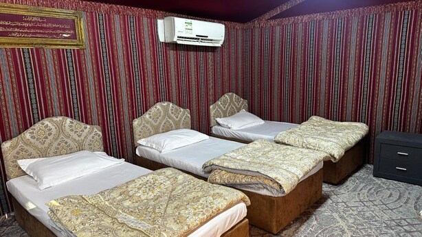 Une chambre d’hôtel avec trois lits, une moquette à motifs et un appareil de climatisation.