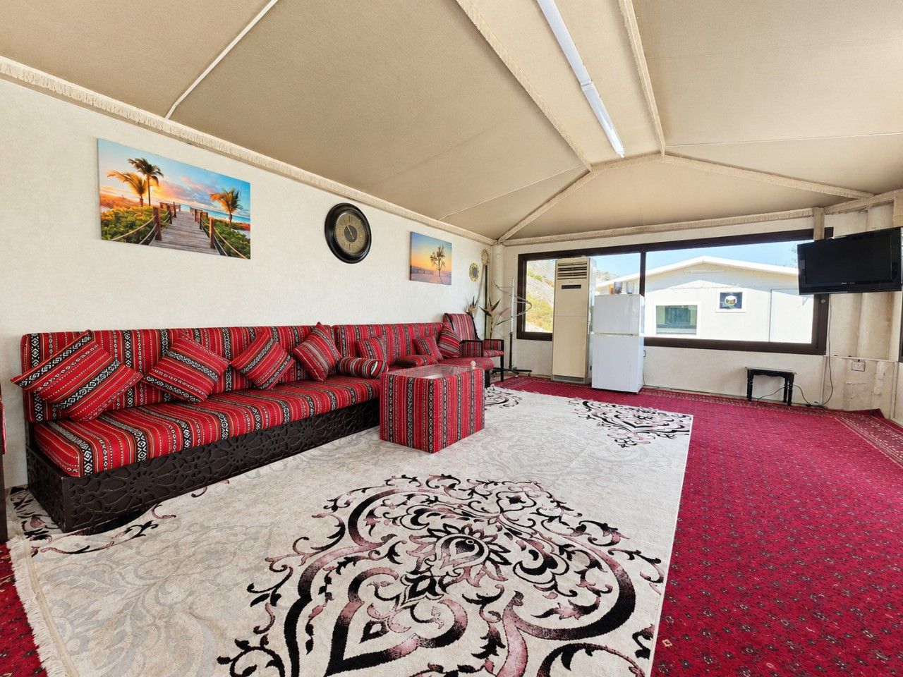 A room with a sofa, ottoman, and a large patterned rug.