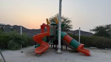 A playground with two slides and a climbing structure.
