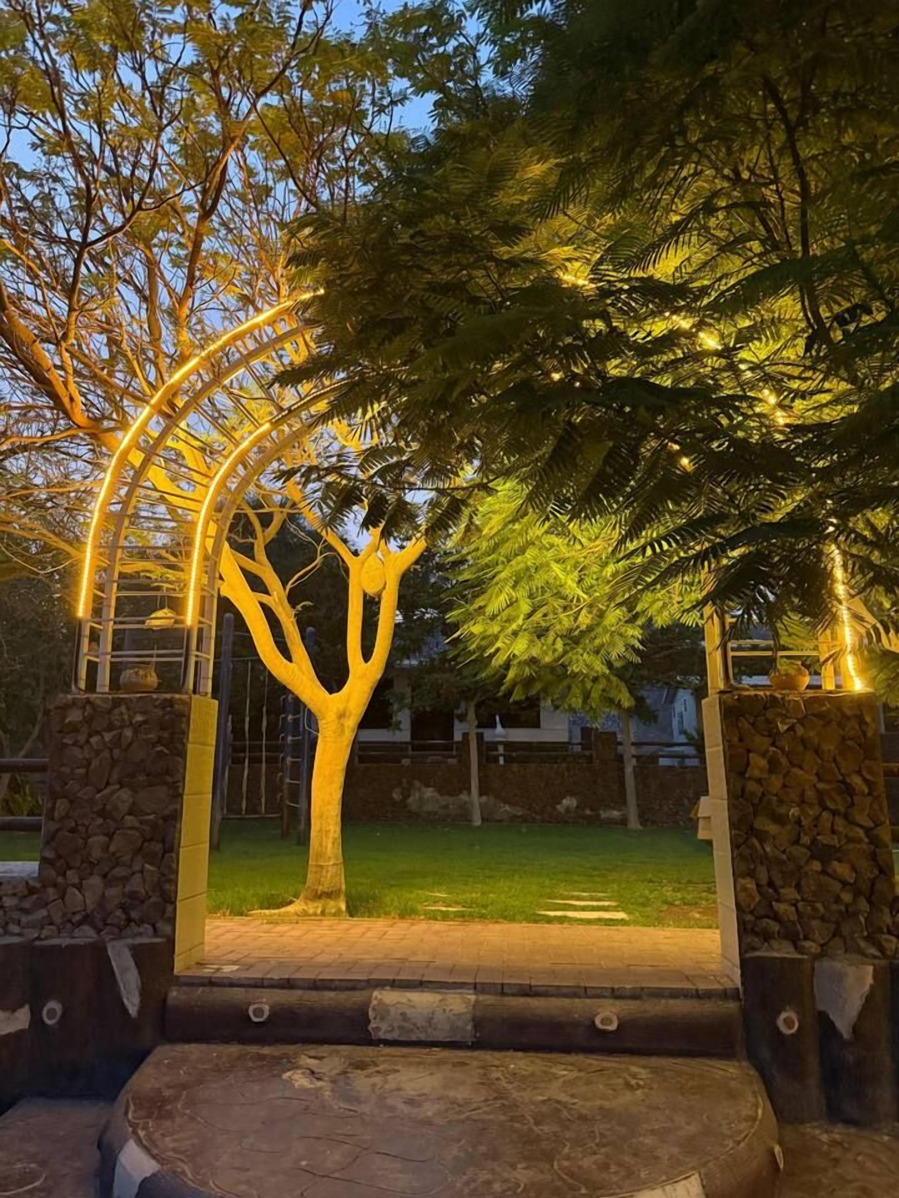 A tree with a stone base and a metal archway.