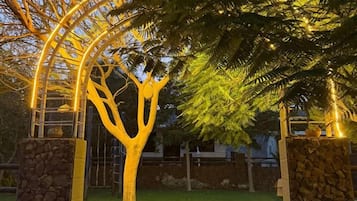 A tree with a stone base and a metal archway.