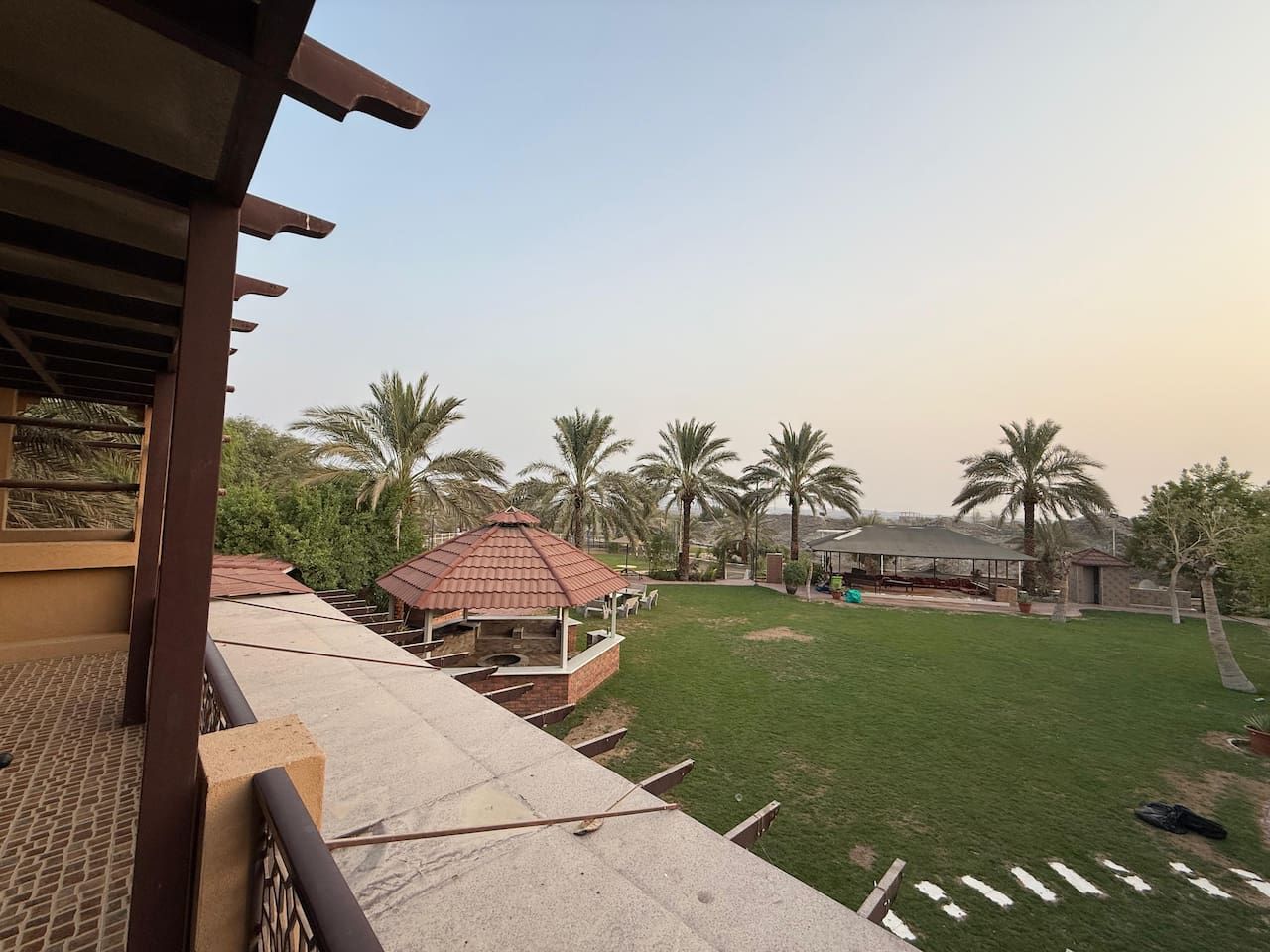 A rooftop terrace with a barbecue area, palm trees, and a gazebo.