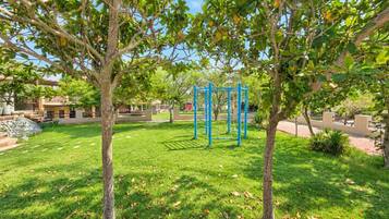 A park with a playground, trees, and a building in the background.