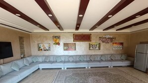 Un salon avec un canapé d’angle, une grande moquette et des œuvres d’art accrochées aux murs.