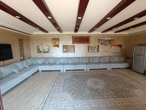Una sala de estar con un sofá seccional, una alfombra grande y obras de arte en las paredes.