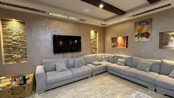 Una sala de estar moderna con un sofá modular, un televisor de pantalla plana, arte decorativo en la pared y suelo de mármol.