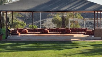 A covered outdoor seating area with a view of a mountainous landscape.