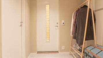 A hallway with a door, a coat rack, and a suitcase.