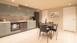 Cozinha moderna com armários cinza, mesa de jantar com cadeiras e um quadro na parede.