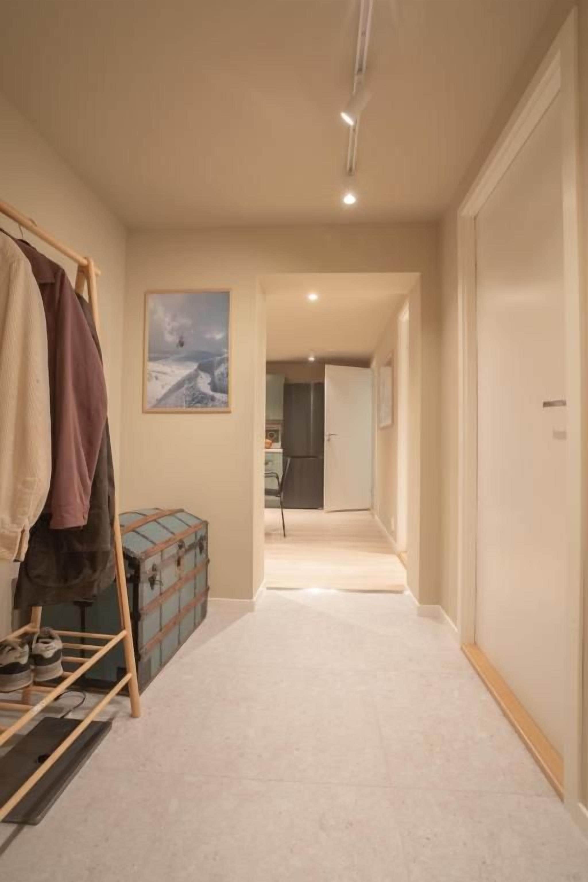 A hallway with a coat rack, a suitcase, and a framed picture on the wall.