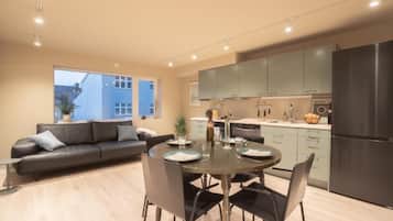 A modern kitchen with a dining area, a sofa, and a view of a building outside.