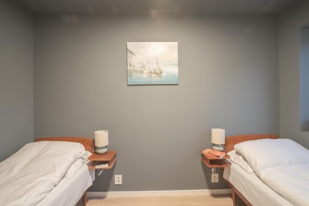 A hotel room with two beds, a painting on the wall, and bedside tables with lamps and books.