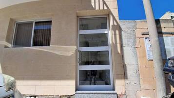 Fachada de un edificio con una ventana transparente, una puerta visible y un letrero que indica 'LOTUNDA APARTMENTS BLOCK B'.