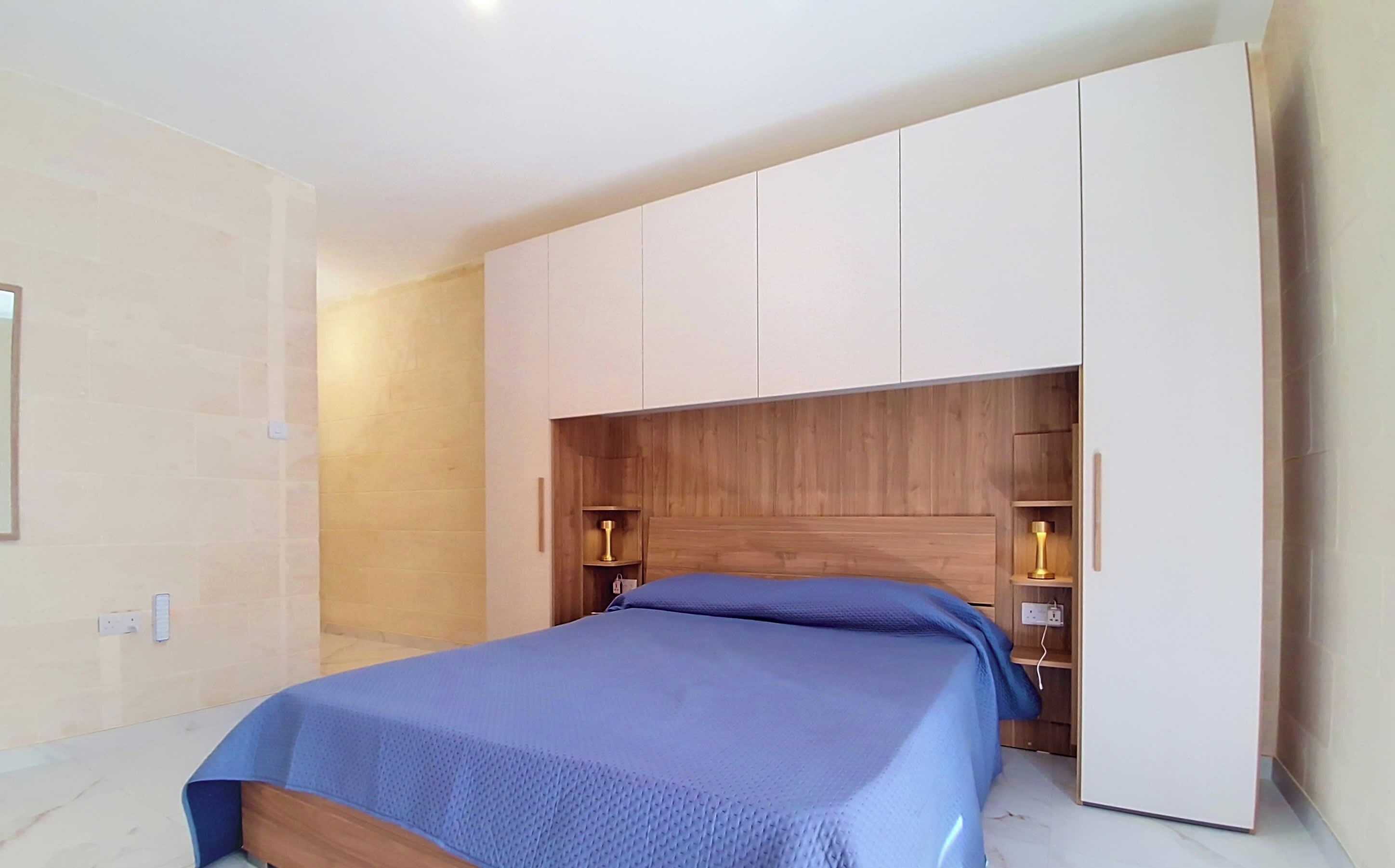 Un dormitorio con una cama, un armario y una mesita de noche.