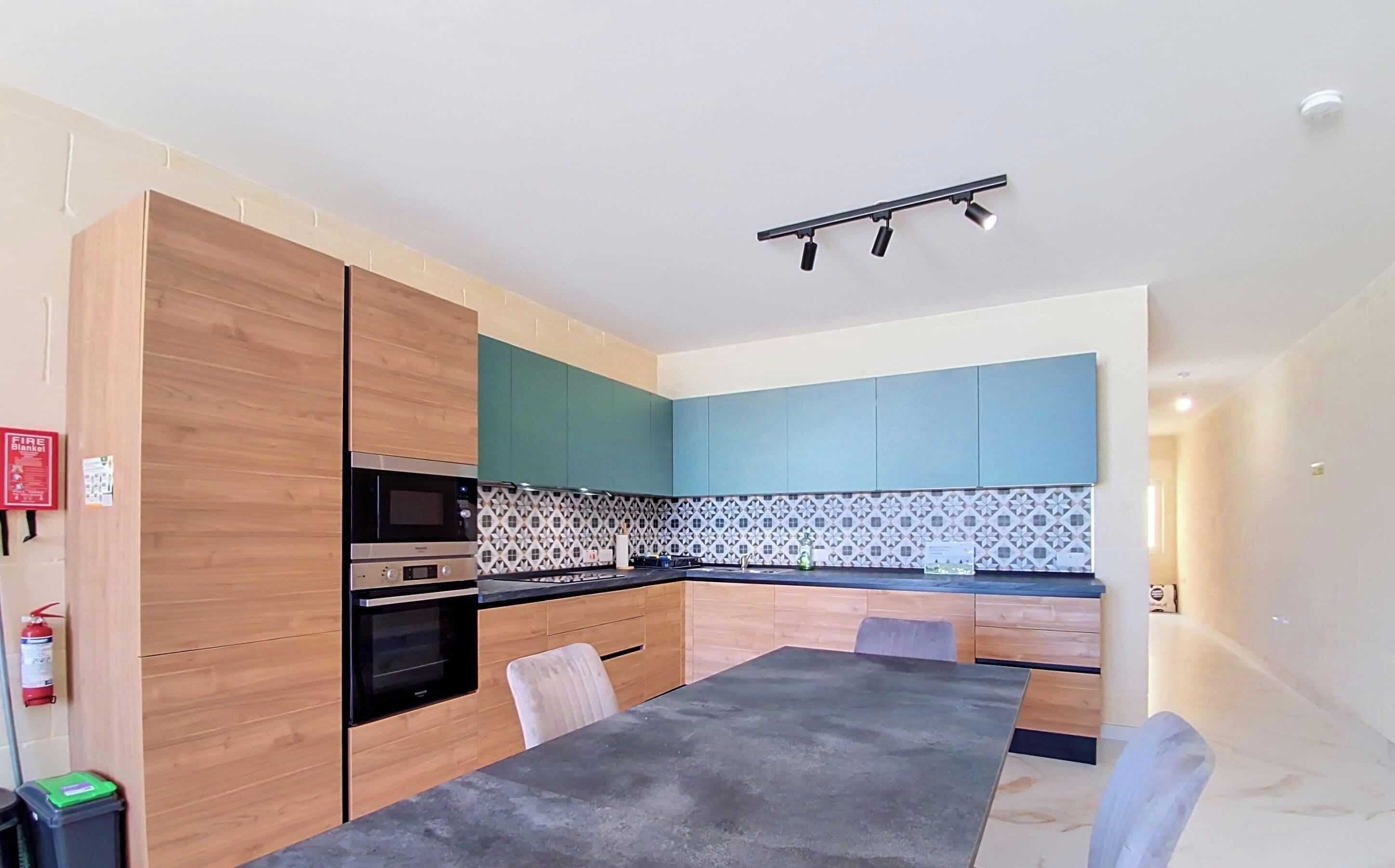 Una cocina moderna con armarios de madera, encimera negra y salpicadero estampado.