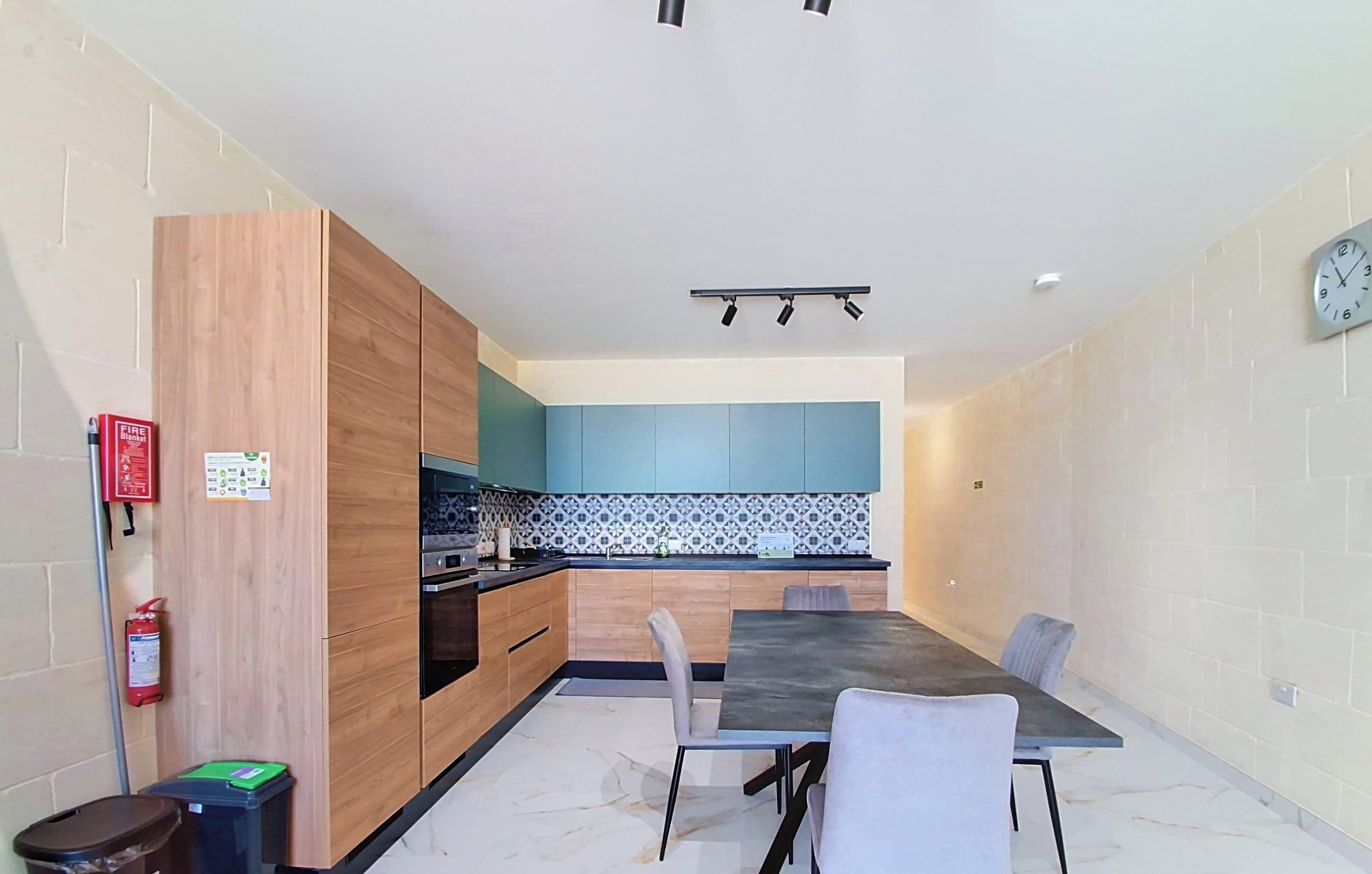 A modern kitchen with wooden cabinets, a black countertop, and a blue backsplash.