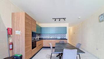 A modern kitchen with wooden cabinets, a black countertop, and a blue backsplash.