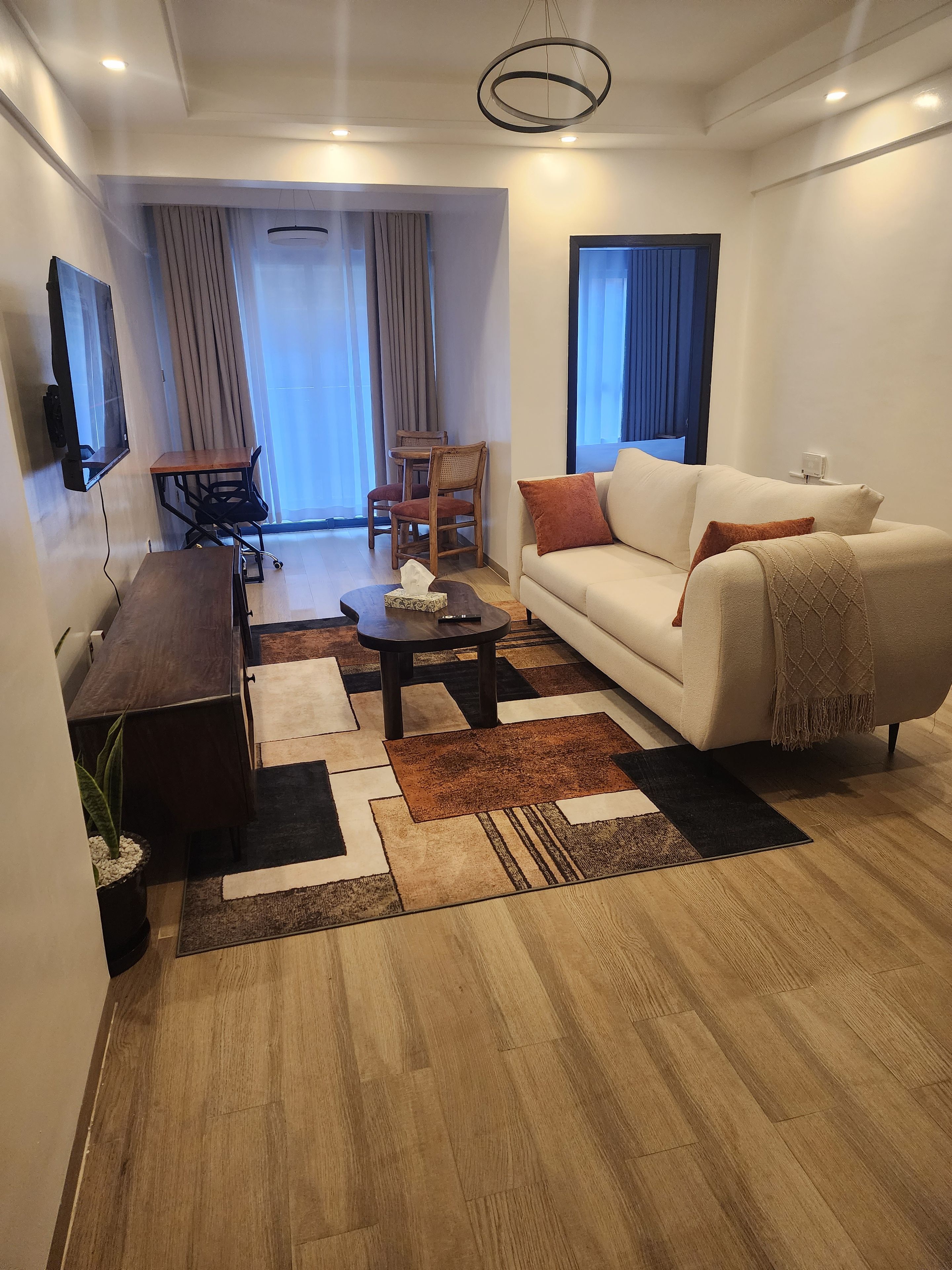 A modern living room with a sofa, coffee table, and a dining area with chairs.