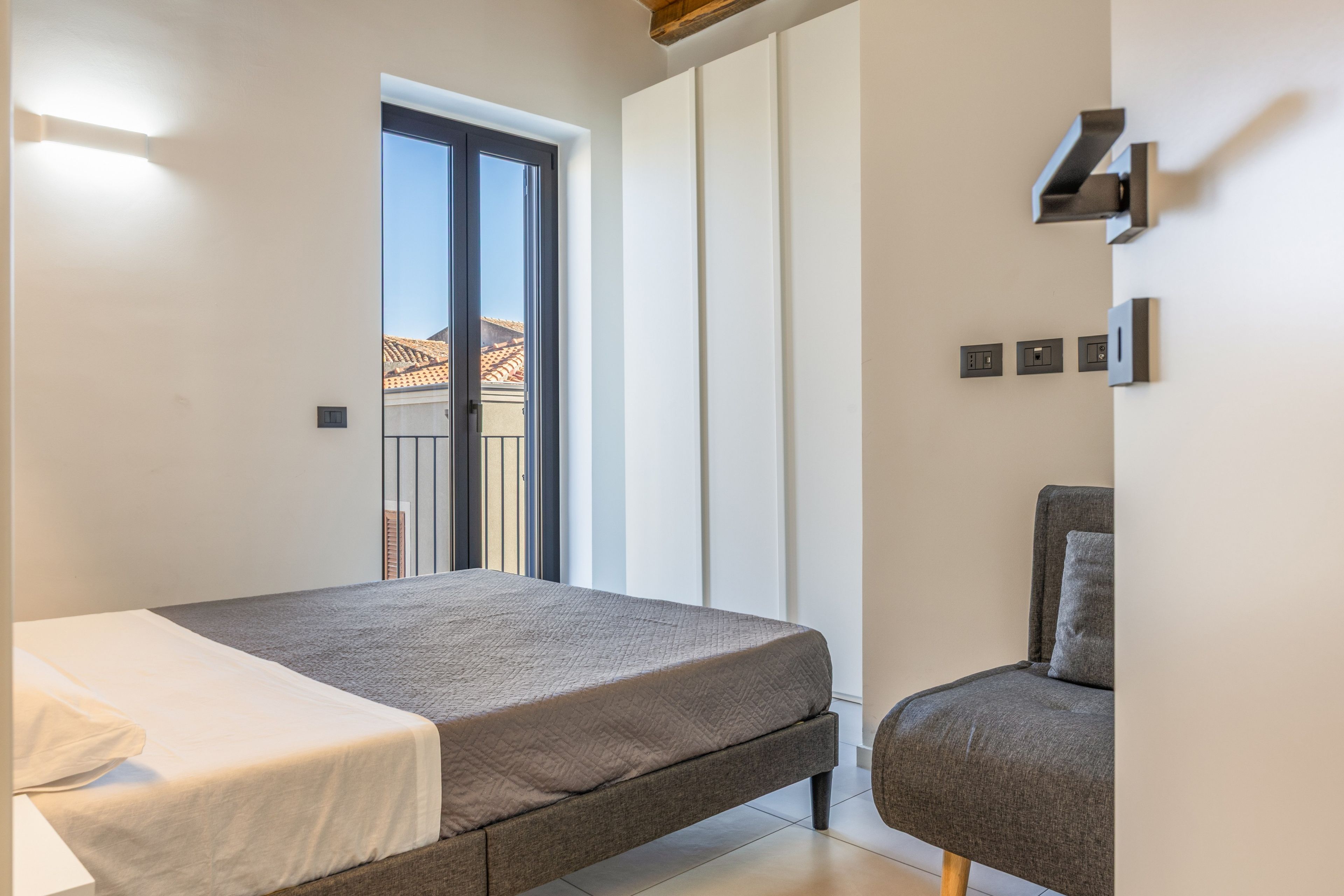 Une chambre à coucher avec un lit, une chaise, une fenêtre et une porte.