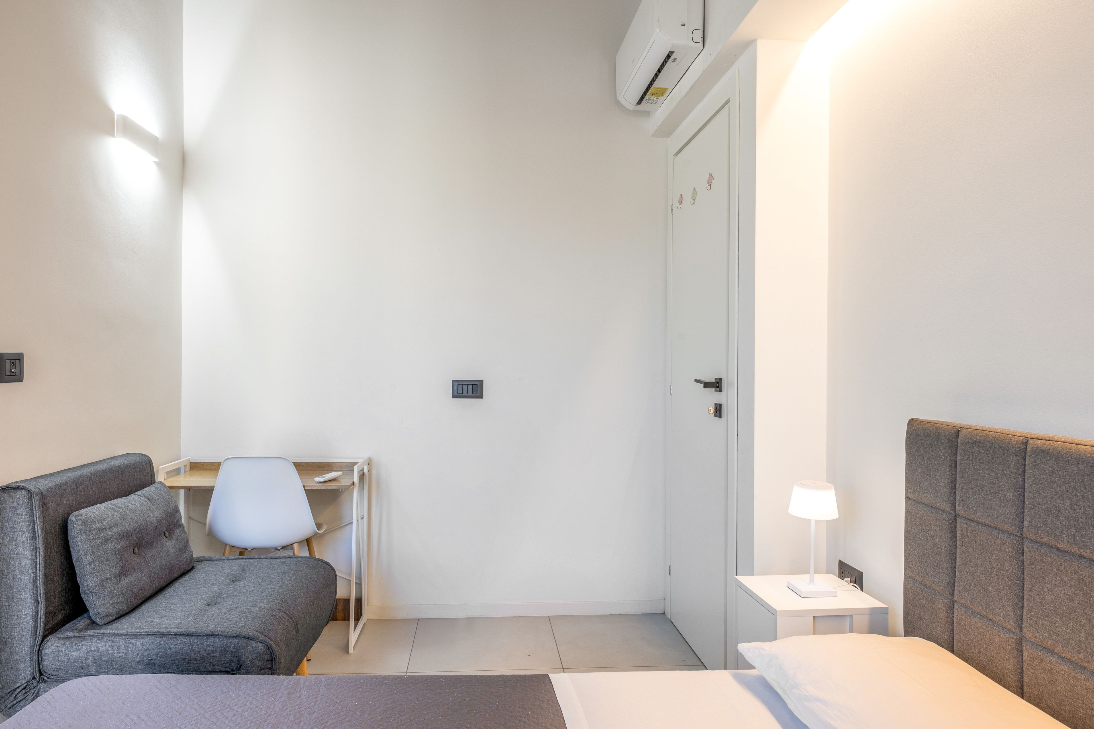 A hotel room with a bed, a desk, a chair, and a nightstand.