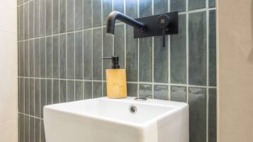 A bathroom with a white pedestal sink, a black faucet, and a wooden soap dispenser.