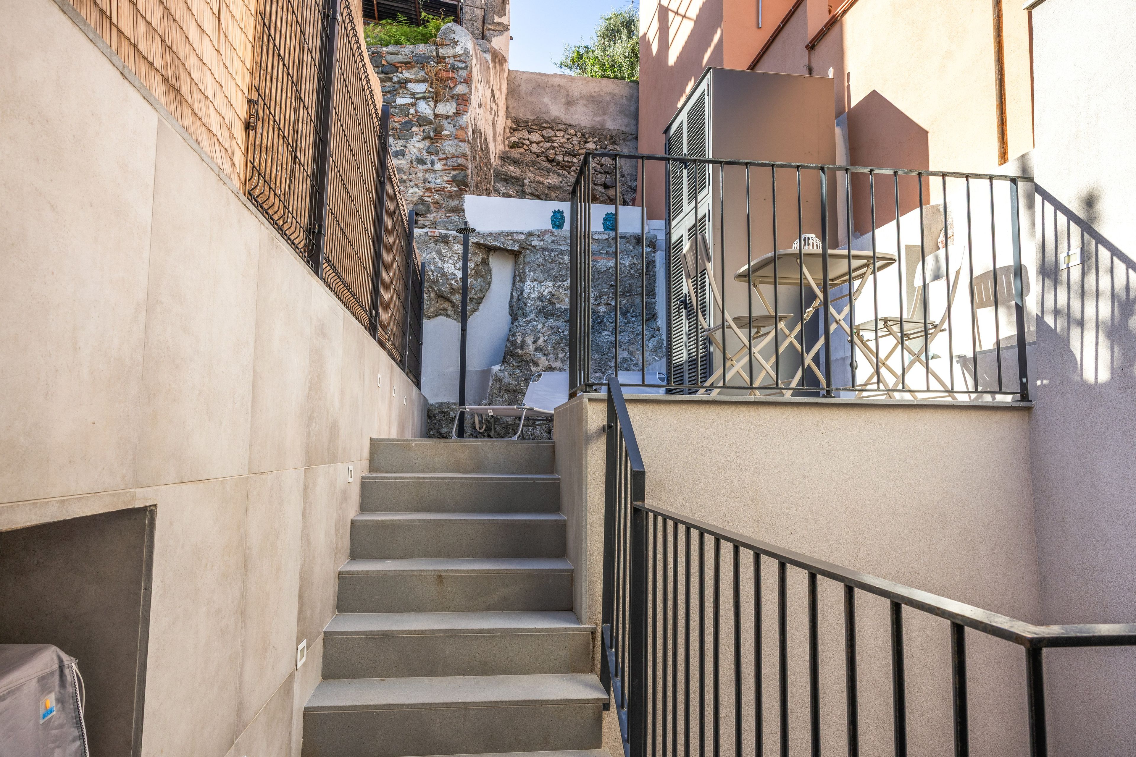 Una escalera que lleva a un balcón con muebles de exterior.