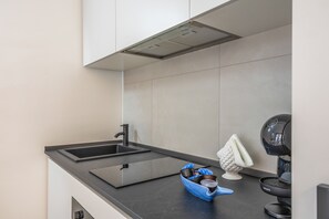 A modern kitchen with a black countertop, a stainless steel sink, and a coffee machine.