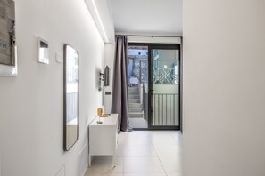 A modern interior with a white wall, a small white table, a mirror, and a sliding glass door leading to a balcony with outdoor furniture. - Calcagno Home vacation house with private terrace, Wi-Fi, and air conditioning (Milazzo)