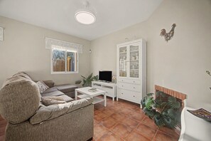 Una sala de estar con sofá, una mesa de centro, televisor, aparador con puertas de vidrio y chimenea.